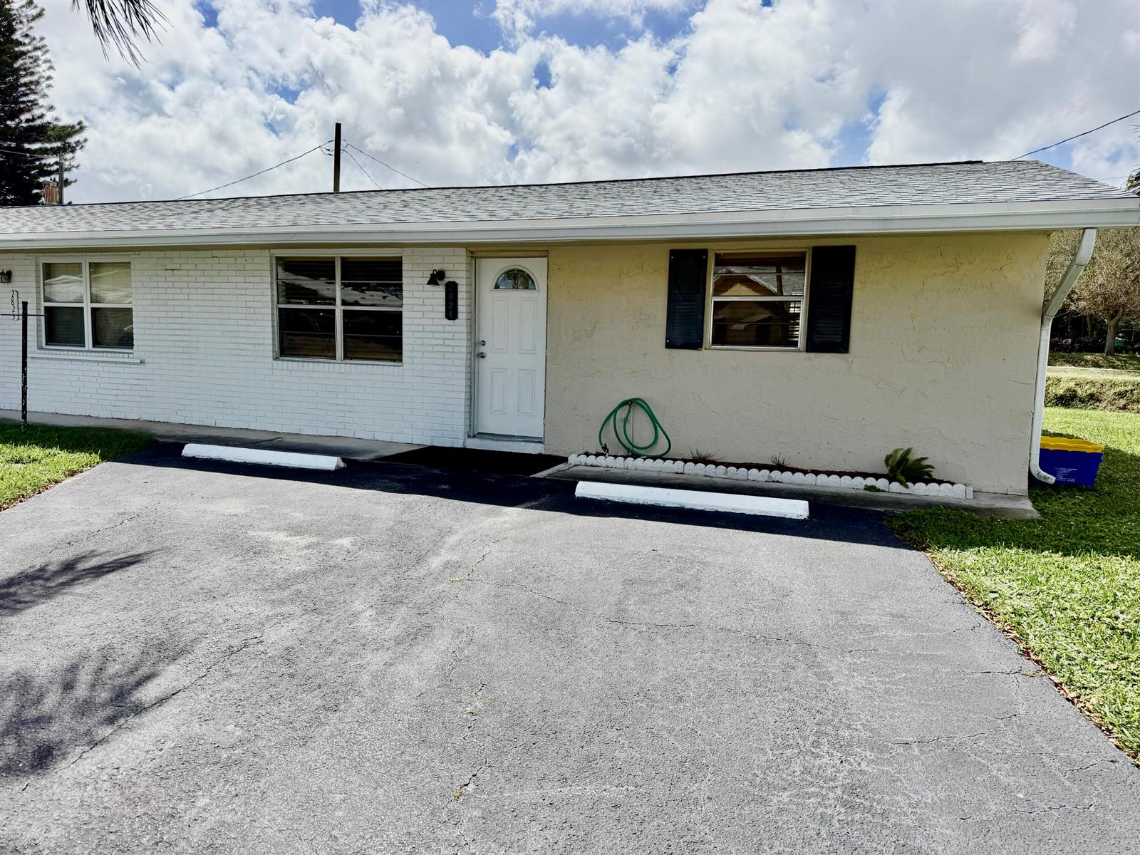 A single-story house with a white brick and beige stucco exterior features a paved driveway — 2821 Duke Lane, Delray Beach FL 33445, DELRAY BEACH, FL