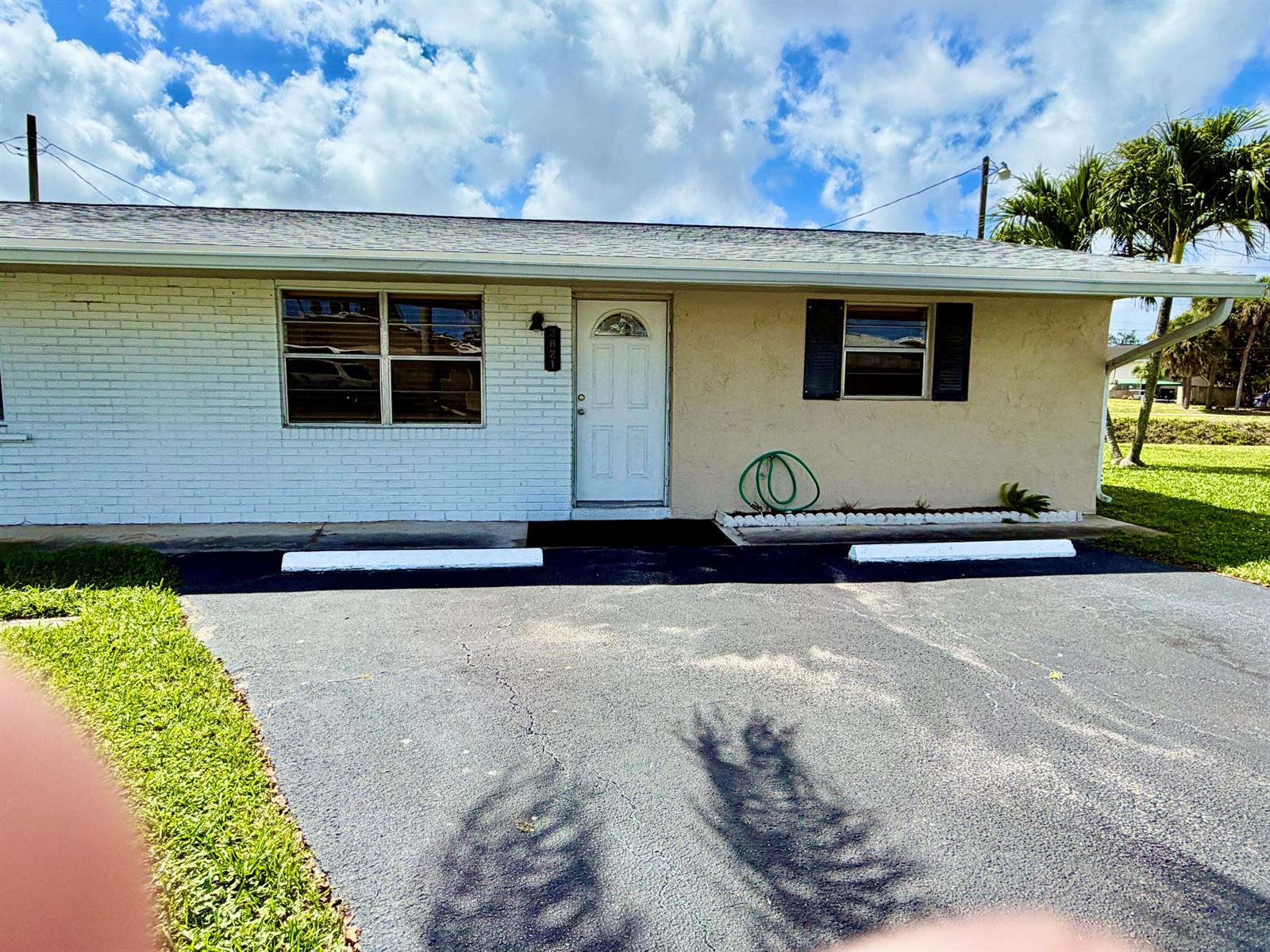 A single-story house with a white brick facade, a front door, and an asphalt driveway — 2821 Duke Lane, Delray Beach FL 33445, DELRAY BEACH, FL