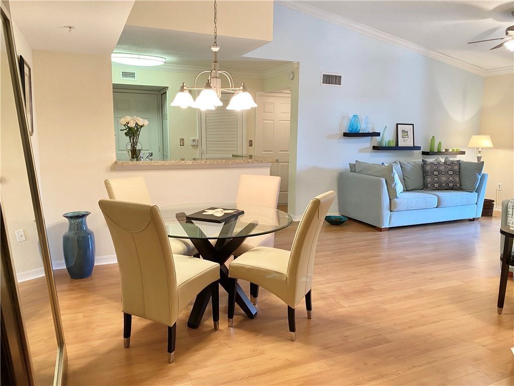 A dining area with a glass table and four chairs sits before a living room — 15035 Michelangelo Boulevard # 306, Delray Beach FL 33446, DELRAY BEACH, FL