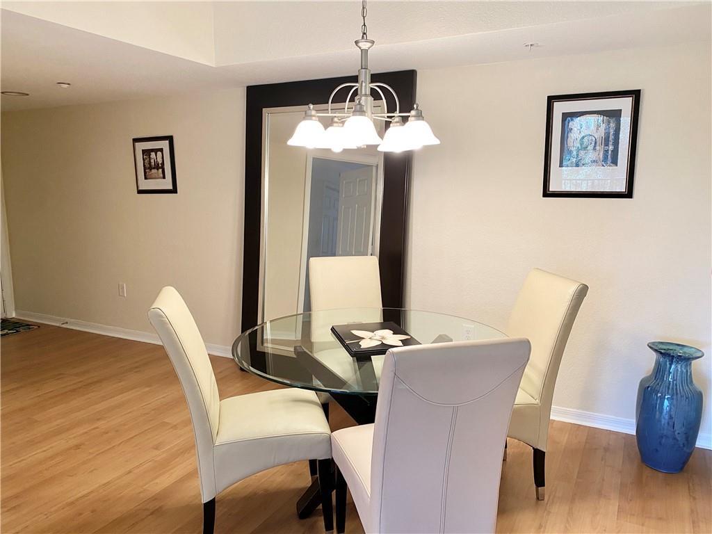 A dining area features a glass-topped table, four cream chairs, and a large wall mirror — 15035 Michelangelo Boulevard # 306, Delray Beach FL 33446, DELRAY BEACH, FL
