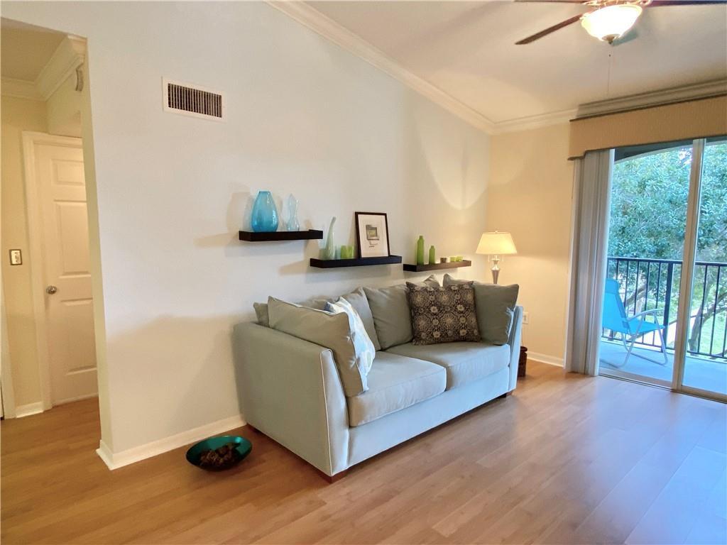 A living room features a light blue sofa, floating shelves, and a sliding glass door — 15035 Michelangelo Boulevard # 306, Delray Beach FL 33446, DELRAY BEACH, FL
