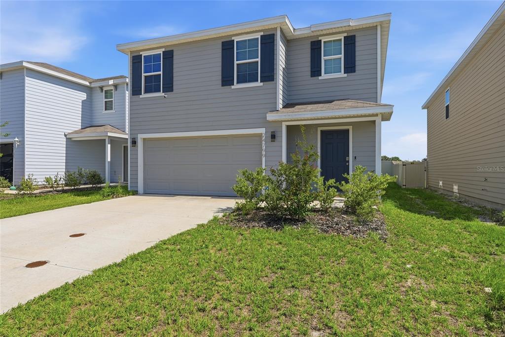A two-story gray house with a two-car garage and a small front yard — 24799 NW 11TH PLACE, NEWBERRY, FL