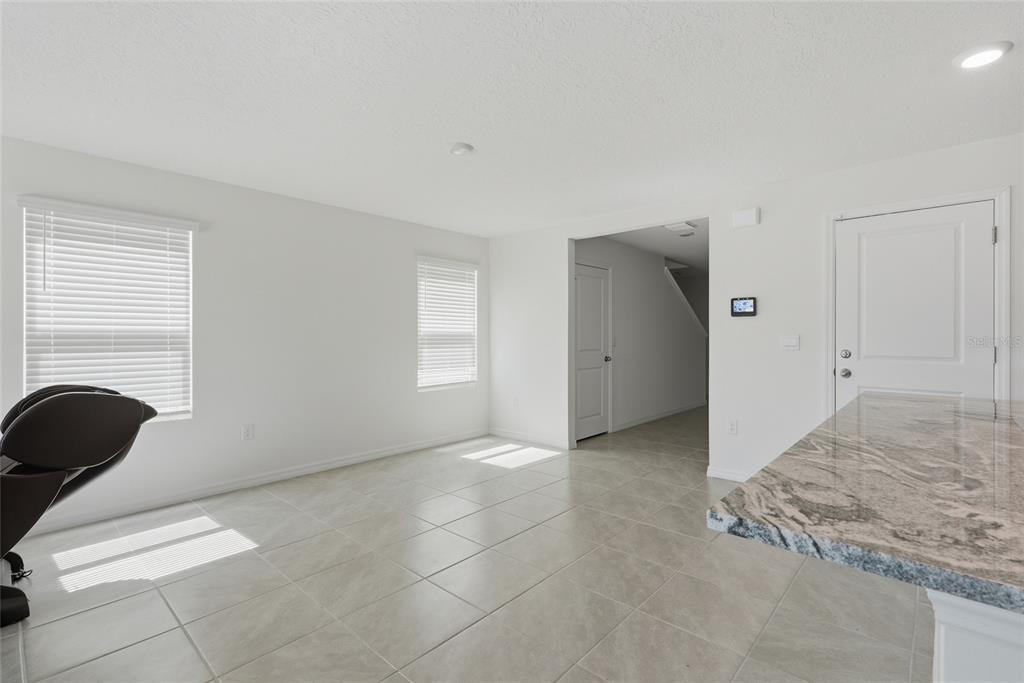 A bright room with tiled floors, two windows, and a granite-topped kitchen island — 24799 NW 11TH PLACE, NEWBERRY, FL