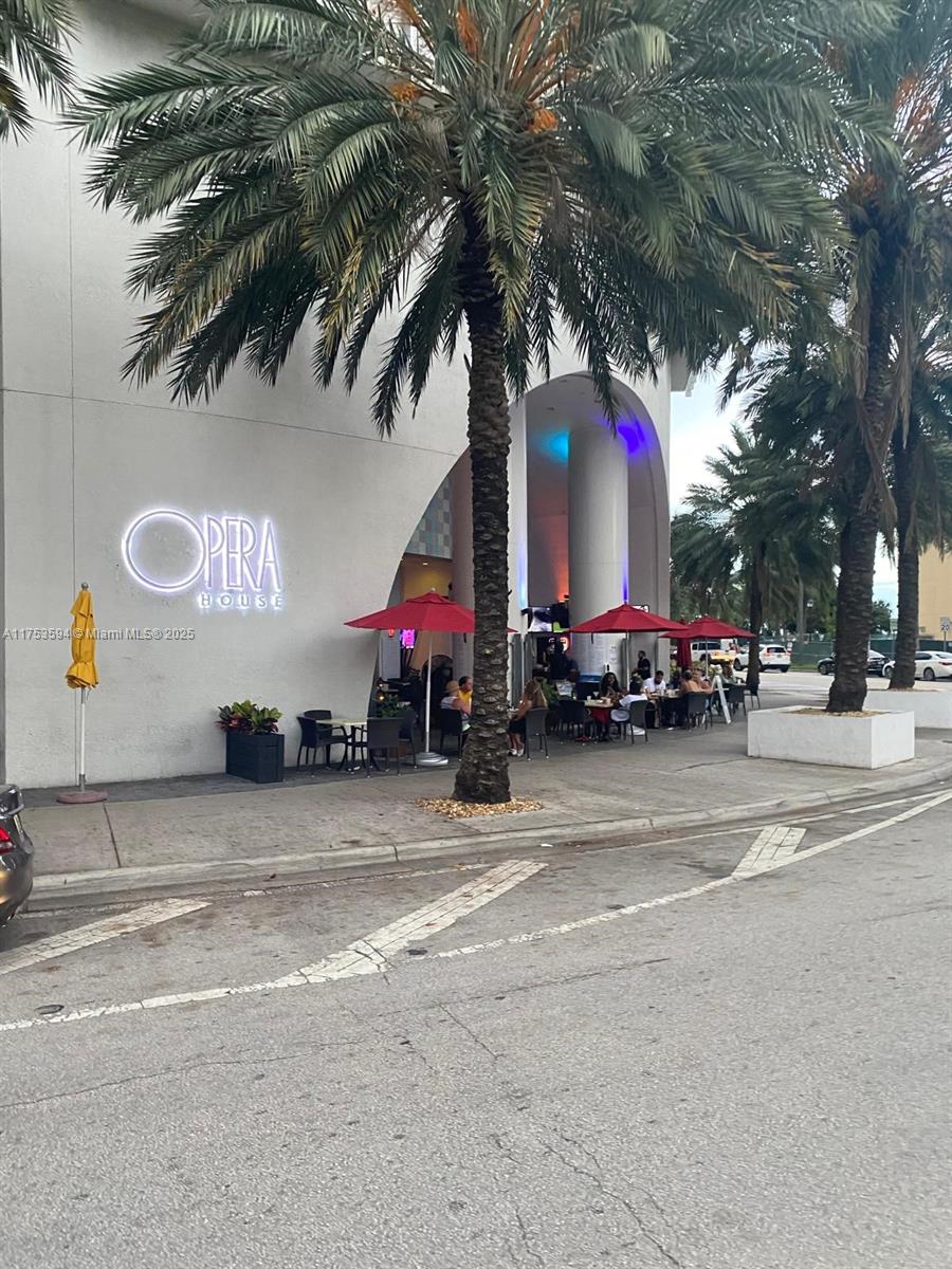An outdoor patio area with red umbrellas and seating sits in front of the Opera House — 1750 N Bayshore Dr # 2905, Miami FL 33132, MIAMI, FL