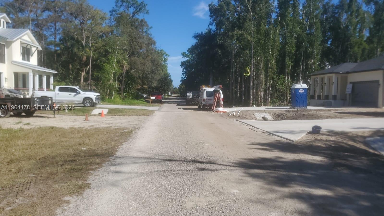 A gravel road runs between two houses with a white van and portable toilet nearby — 3050 Pine Tree Dr, Naples FL 34112, NAPLES, FL