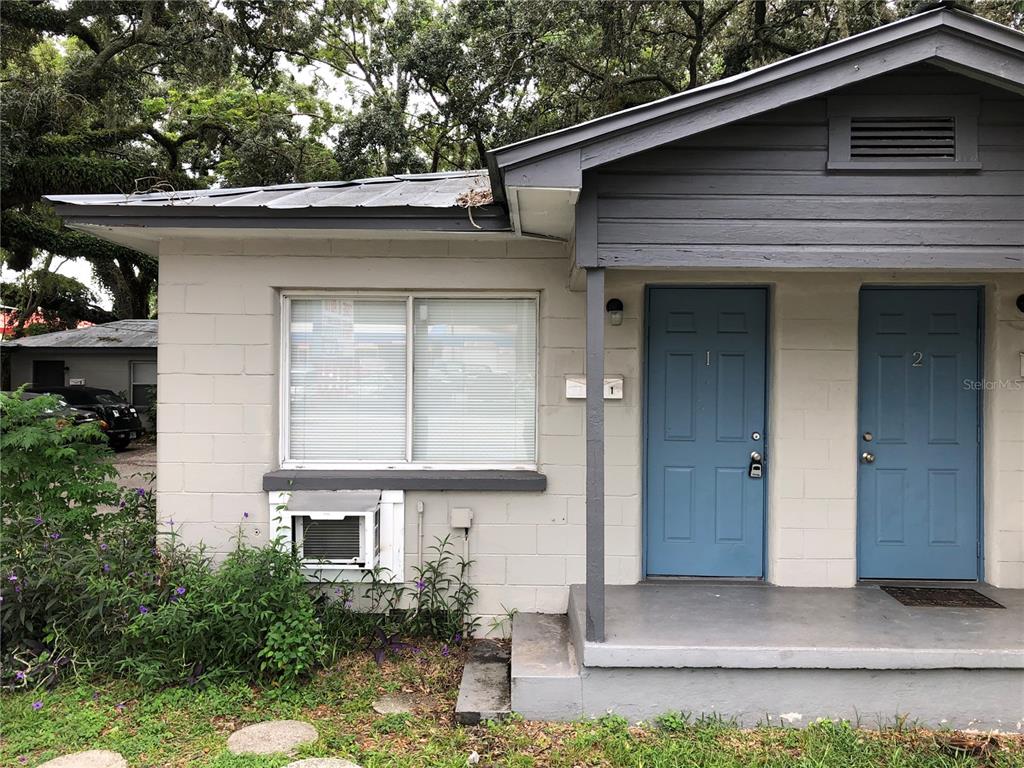 The exterior of a single-story duplex features light-colored concrete block walls and two blue doors — 7208 N NEBRASKA AVENUE UNIT 1, TAMPA, FL
