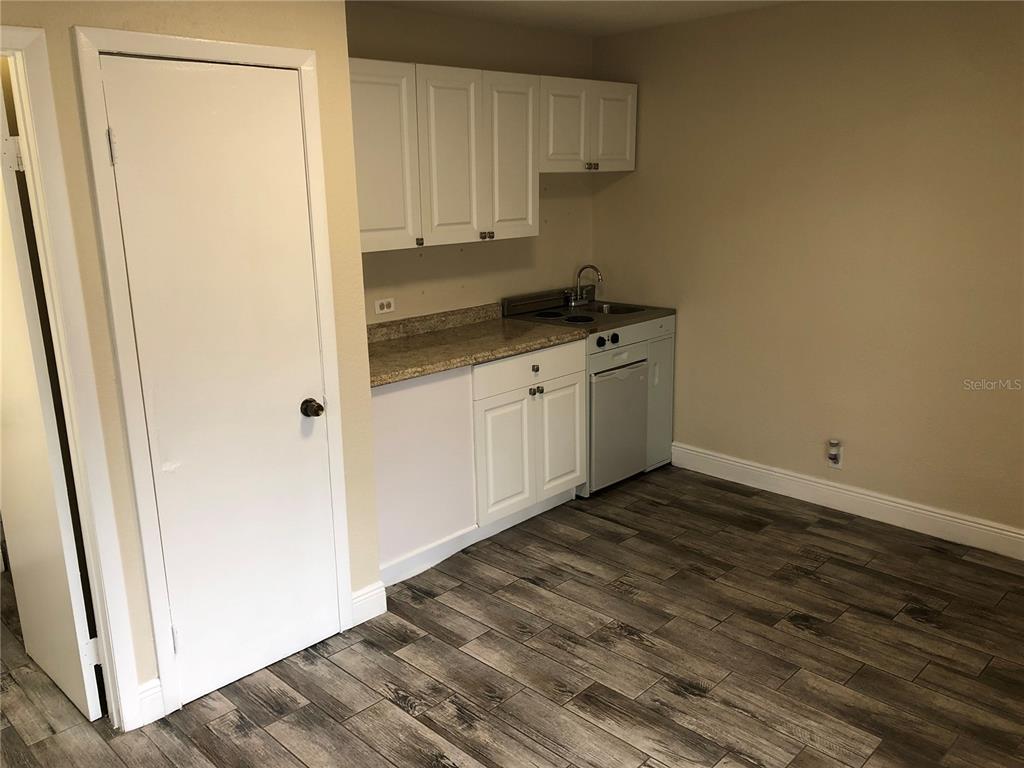 A small kitchenette features white cabinets, a granite countertop, and wood-look tile flooring — 7208 N NEBRASKA AVENUE UNIT 1, TAMPA, FL