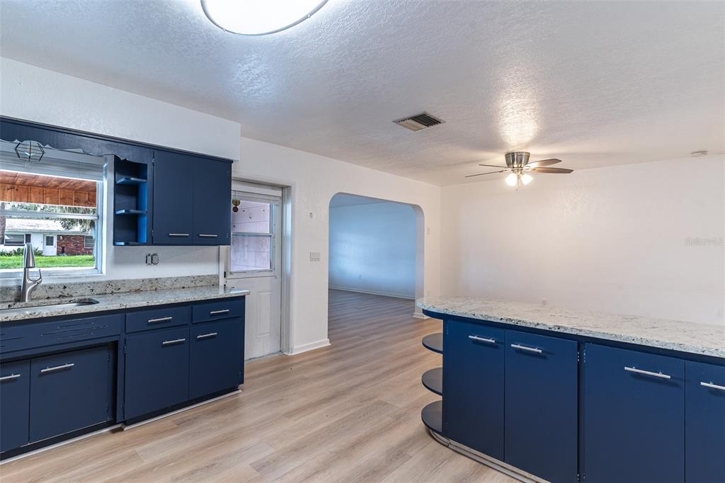 A kitchen features blue cabinets, granite countertops, and light wood-look flooring — 145 BEVERLY DRIVE, WINTER HAVEN, FL