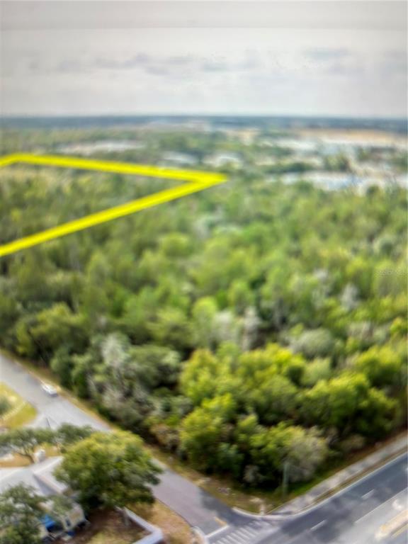 An aerial view shows a wooded lot outlined in yellow near a paved road — N/A SW 20TH STREET, OCALA, FL