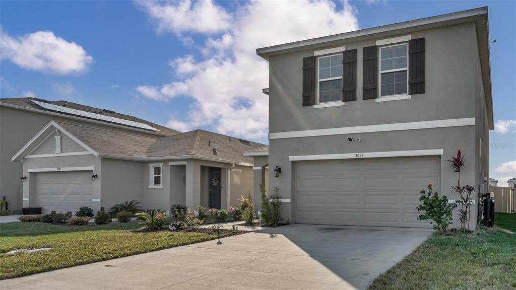 A two-story gray house with a two-car garage stands next to a single-story home — 3097 SUNCOAST PLAINS DRIVE, ODESSA, FL