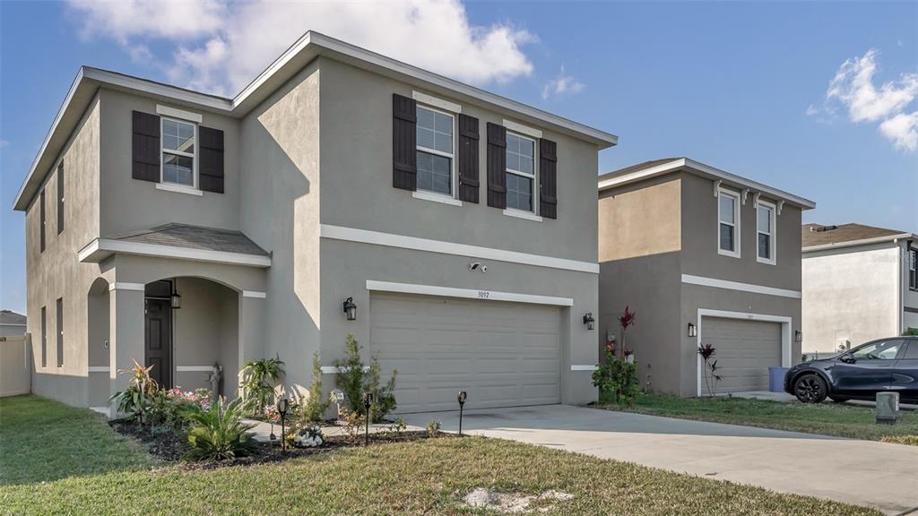A two-story house with a gray stucco exterior, dark shutters, and an attached two-car garage — 3097 SUNCOAST PLAINS DRIVE, ODESSA, FL