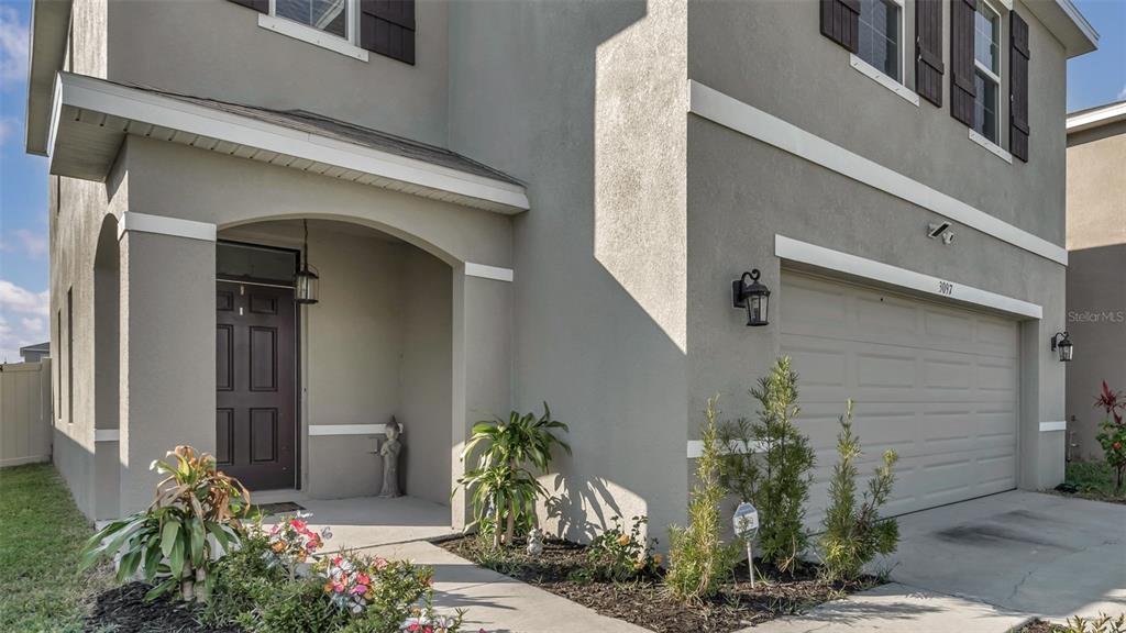 A two-story house exterior features a gray stucco facade, a garage, and a front porch — 3097 SUNCOAST PLAINS DRIVE, ODESSA, FL