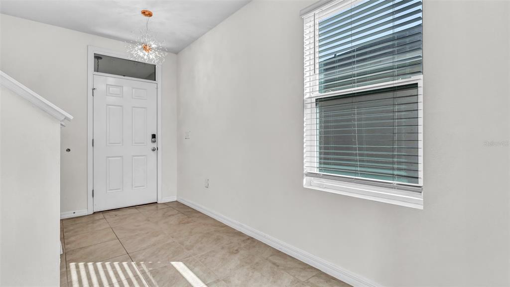 An entryway features a white front door, tiled flooring, a modern light fixture, and a window — 3097 SUNCOAST PLAINS DRIVE, ODESSA, FL