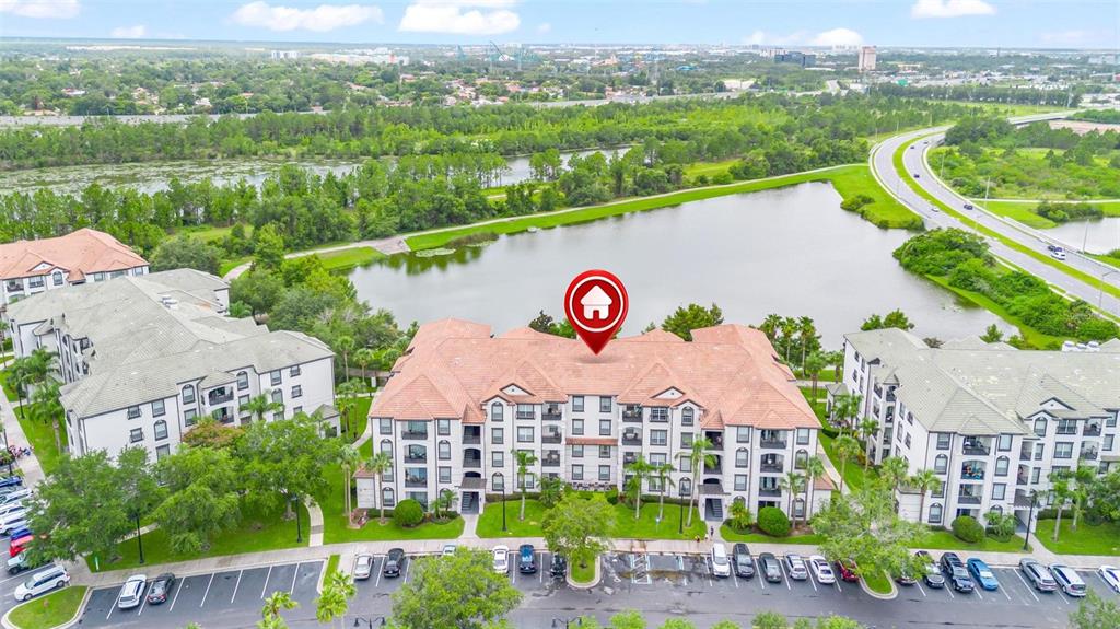 An aerial view shows a multi-story apartment complex with a tiled roof beside a lake — 4114 BREAKVIEW DRIVE UNIT 110, ORLANDO, FL