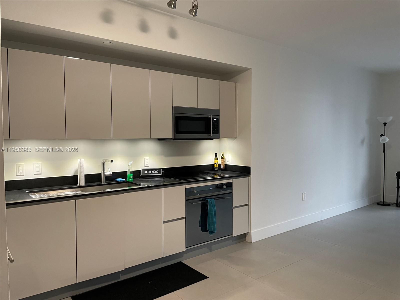 A modern kitchen features light-colored cabinets, black countertops, and stainless steel appliances — 1010 Brickell Ave # 3708, Miami FL 33131, MIAMI, FL