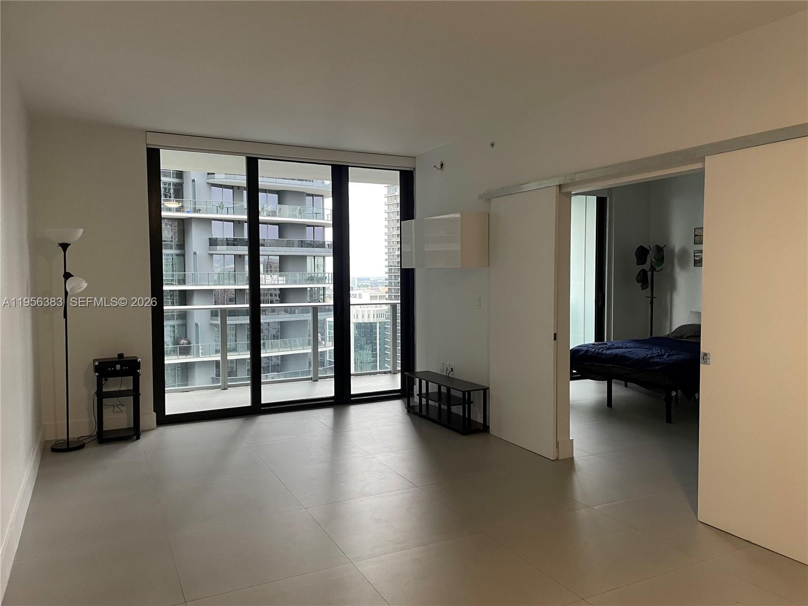 A living room with tile floors and a sliding door leading to a bedroom — 1010 Brickell Ave # 3708, Miami FL 33131, MIAMI, FL