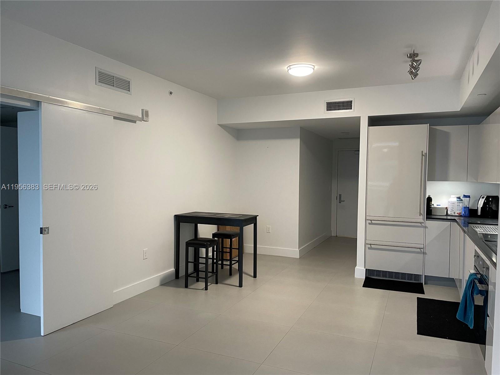 A modern kitchen and dining area feature white walls, light tile flooring, and stainless appliances — 1010 Brickell Ave # 3708, Miami FL 33131, MIAMI, FL