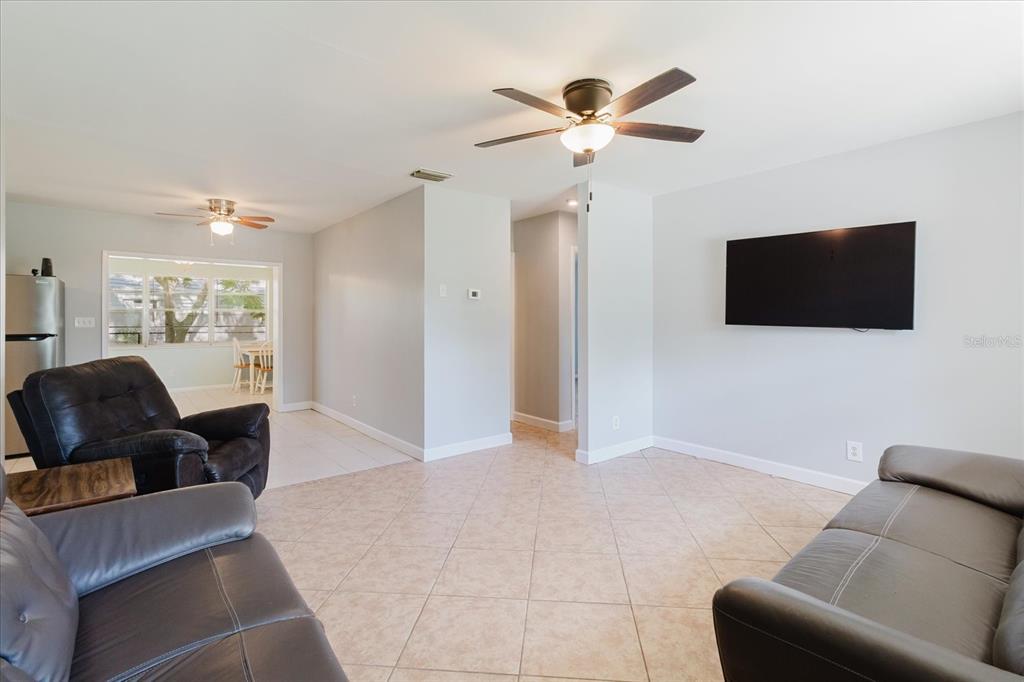 A living room features tile flooring, a ceiling fan, and a wall-mounted television — 6212 FLORIDA CIRCLE W, APOLLO BEACH, FL