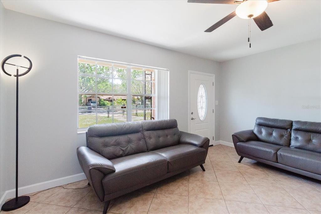 A living room with tile floors, two dark leather sofas, a window, and a ceiling fan — 6212 FLORIDA CIRCLE W, APOLLO BEACH, FL