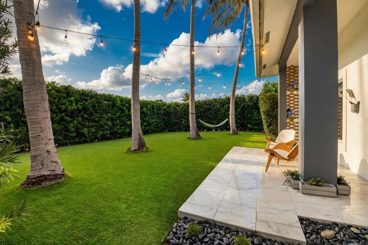 A patio with marble flooring and chairs overlooks a grassy backyard with palm trees — 1044 NW 6th Drive, Boca Raton FL 33486, BOCA RATON, FL