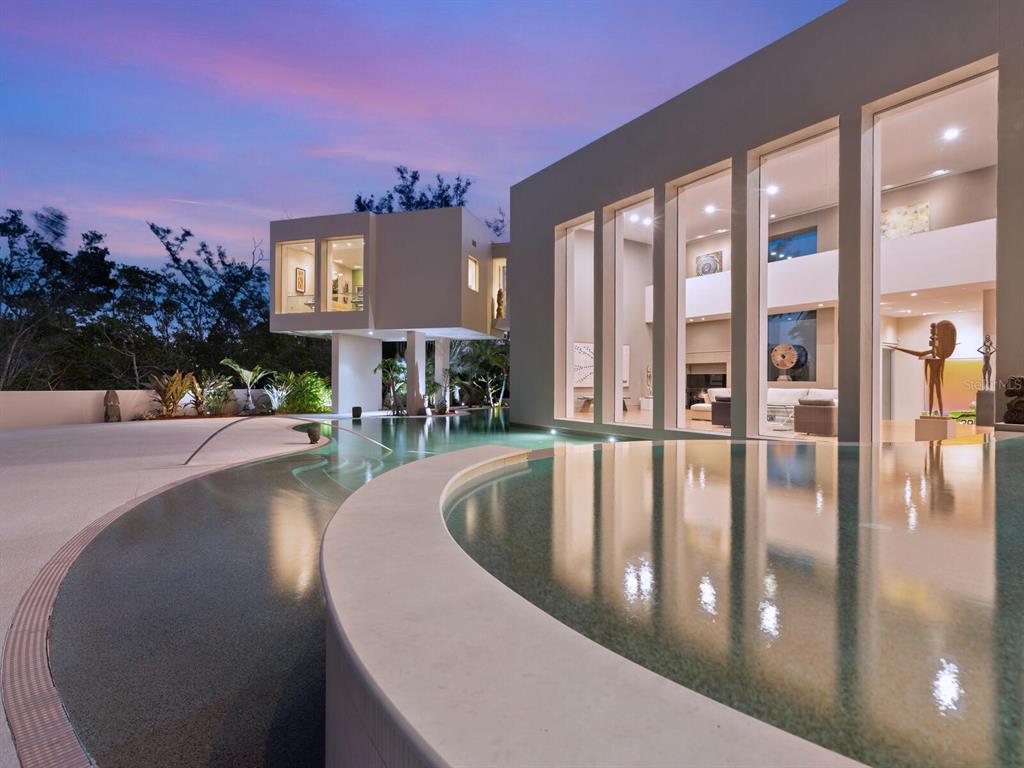 A modern house with a curved infinity pool and a cantilevered room at sunset — 6610 GULF OF MEXICO DRIVE, LONGBOAT KEY, FL