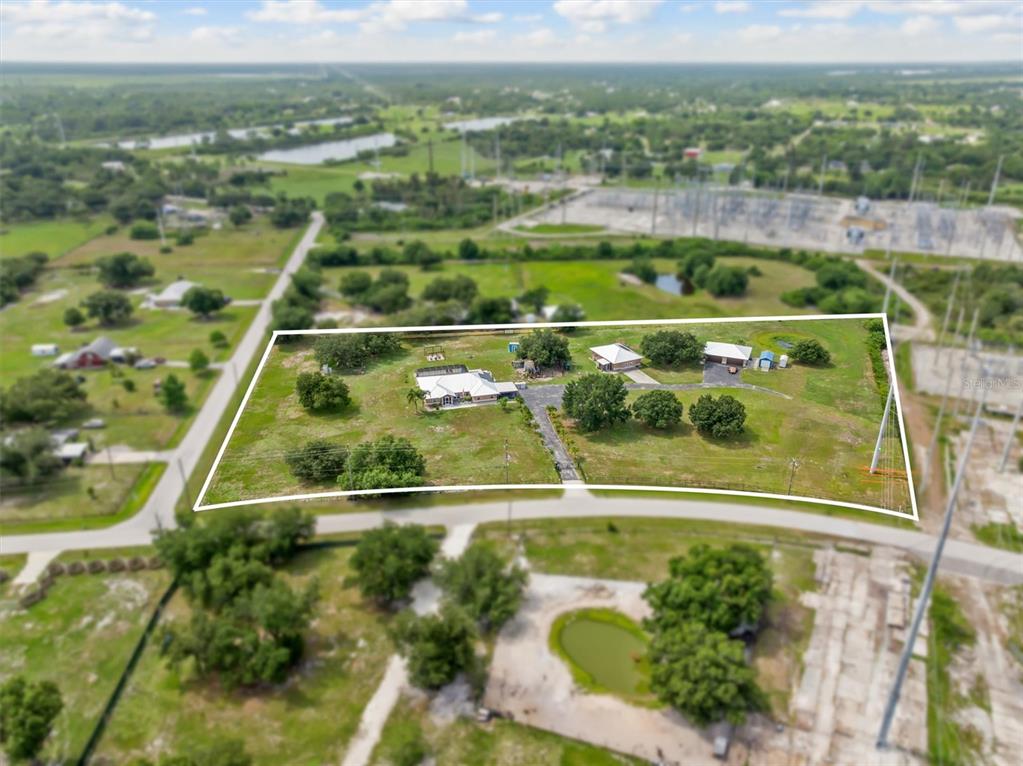 An aerial view shows a house and detached garage on a large, fenced rural lot — 8200 CLEVELAND DRIVE, PUNTA GORDA, FL