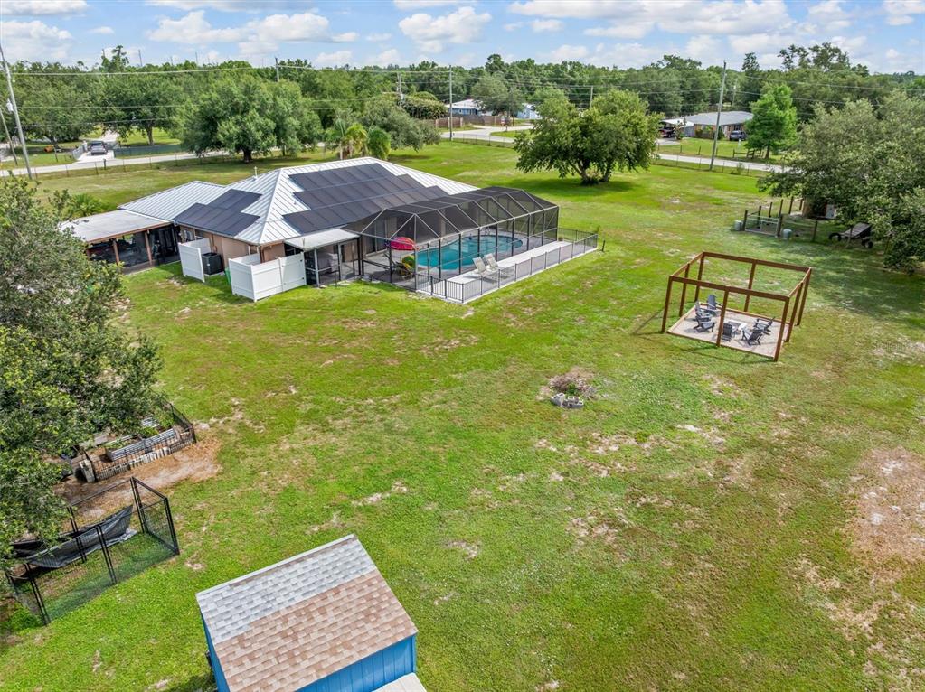 An aerial view shows a house with solar panels, a screened pool, and a large yard — 8200 CLEVELAND DRIVE, PUNTA GORDA, FL