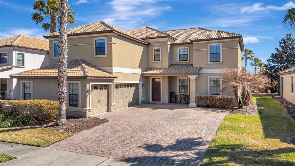 A two-story house with a tan stucco exterior, tile roof, and a paved driveway — 1303 SEA PINES WAY, DAVENPORT, FL
