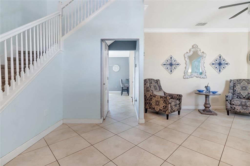 A foyer features a staircase, tiled flooring, and a seating area with two patterned armchairs — 1303 SEA PINES WAY, DAVENPORT, FL