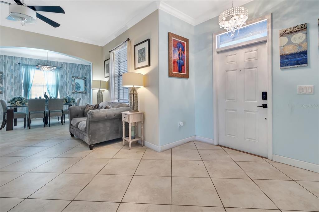 A tiled entryway leads into a dining area with a gray sofa and chandelier — 1303 SEA PINES WAY, DAVENPORT, FL