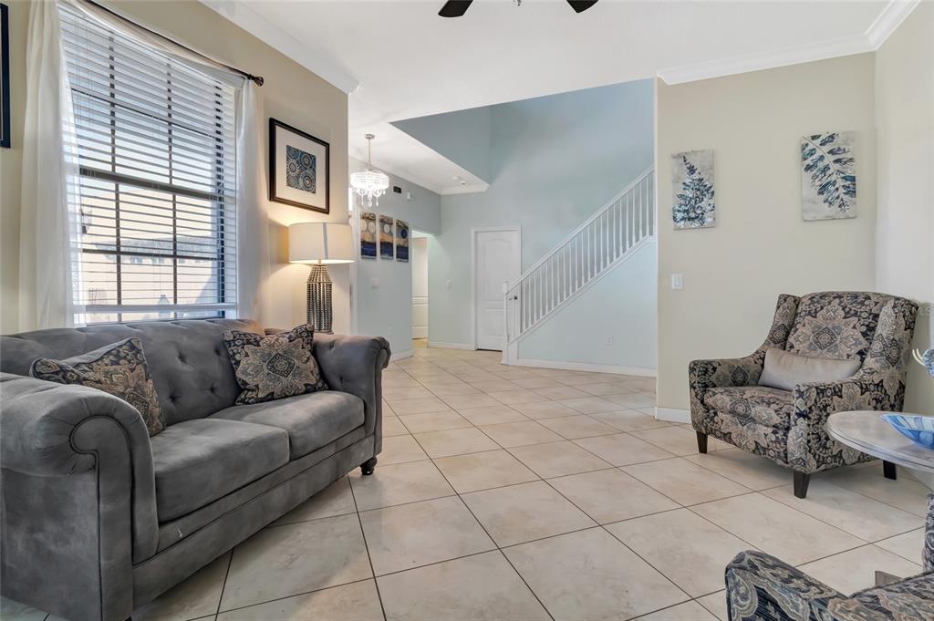 A living room with tile flooring, a gray sofa, an armchair, and a staircase — 1303 SEA PINES WAY, DAVENPORT, FL
