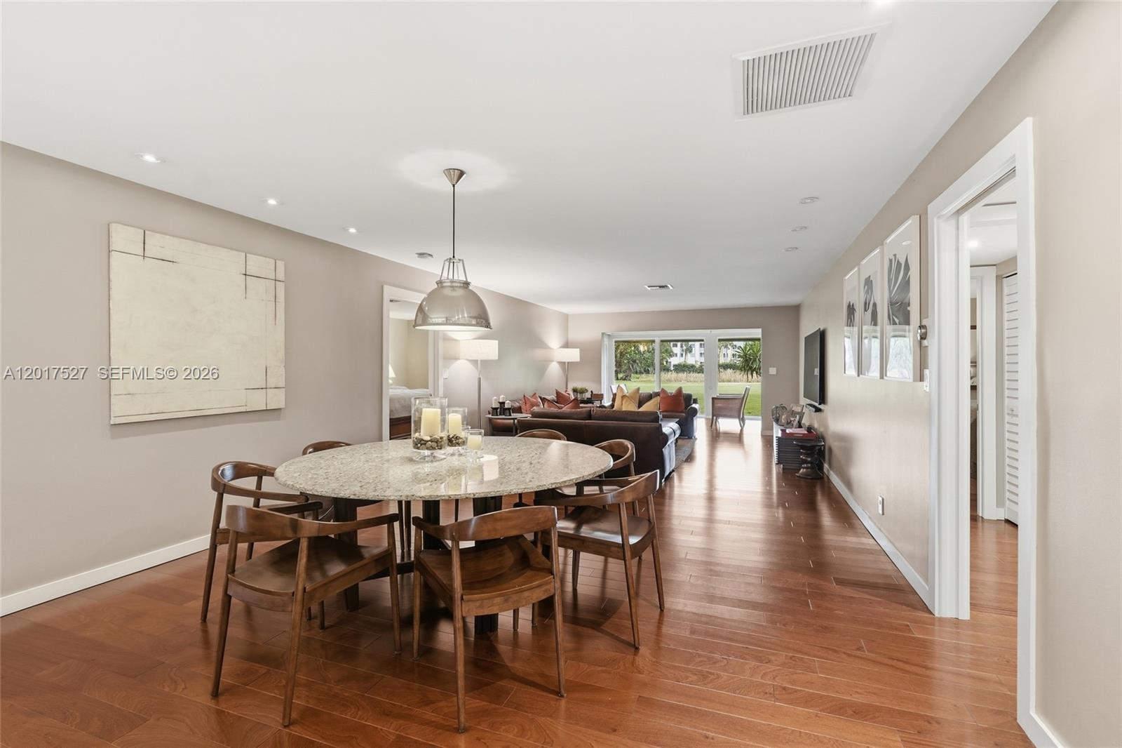 A dining area with a round stone table and wooden chairs opens into a living room — 4002 S Cypress Ln # 17, Pompano Beach FL 33069, POMPANO BEACH, FL