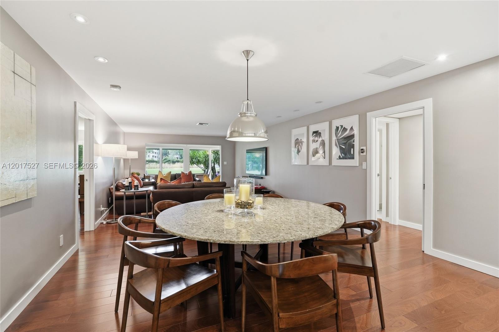 A dining area with a round granite table and wooden chairs sits before a living room — 4002 S Cypress Ln # 17, Pompano Beach FL 33069, POMPANO BEACH, FL