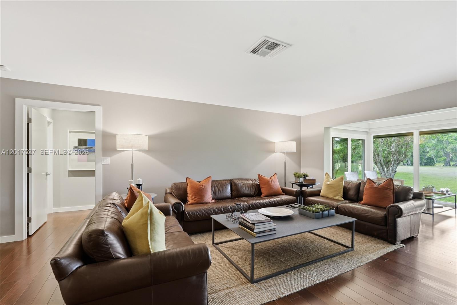 A living room features brown leather sofas, a metal coffee table, and large glass windows — 4002 S Cypress Ln # 17, Pompano Beach FL 33069, POMPANO BEACH, FL