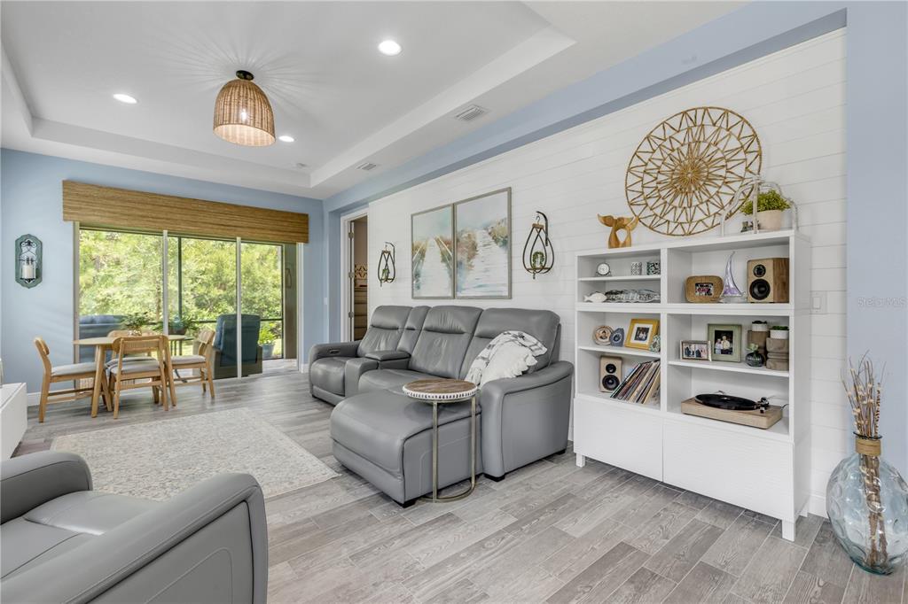 A living room with light blue walls, gray tile flooring, and a sliding glass door — 47 WRENDALE LOOP, ORMOND BEACH, FL