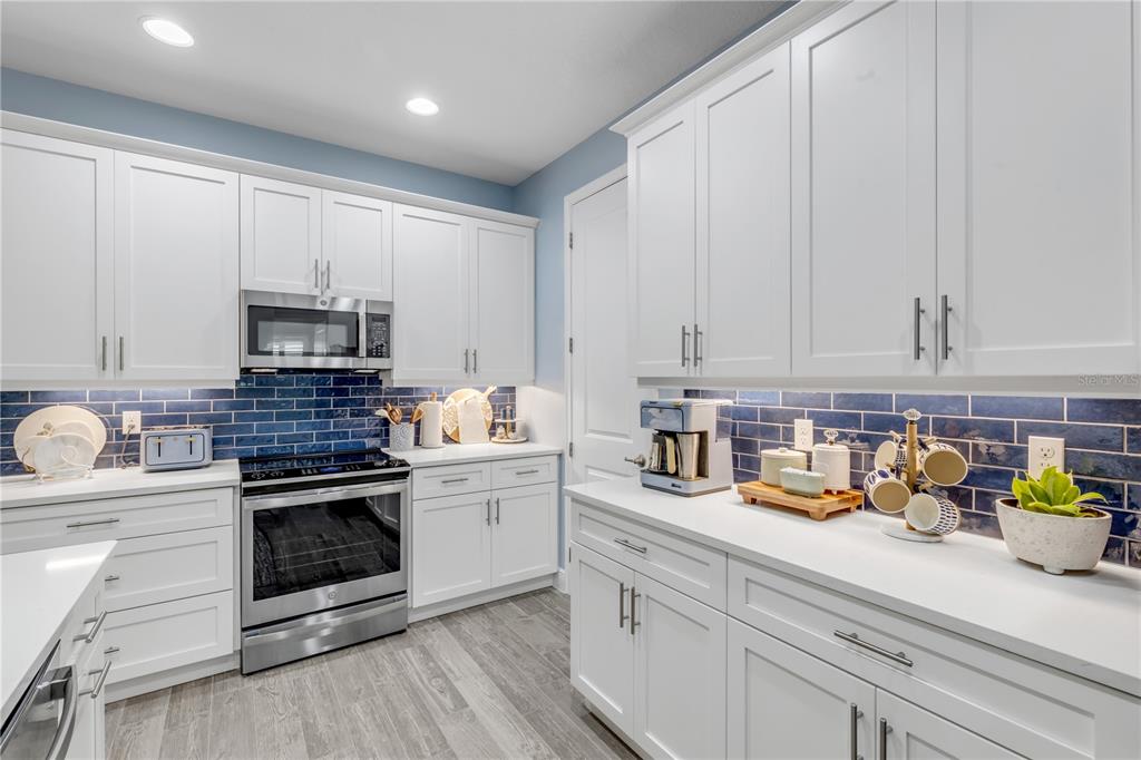 A kitchen and dining area features white cabinetry, a central island, and light blue walls — 47 WRENDALE LOOP, ORMOND BEACH, FL