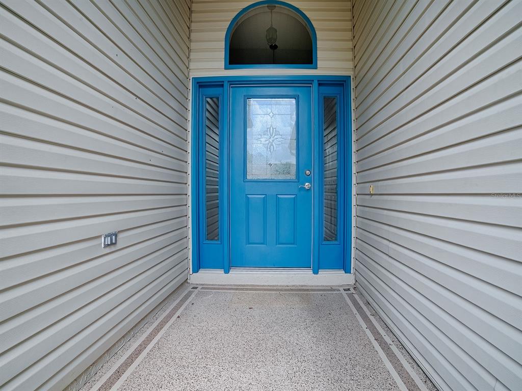 A bright blue front door with a glass insert sits between two sidelights and siding — 1322 GUERRA AVENUE, THE VILLAGES, FL