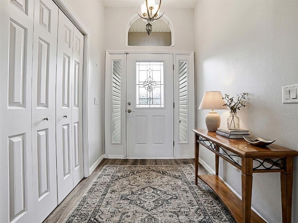 A bright entryway features a white front door with sidelights, a console table, and rug — 1322 GUERRA AVENUE, THE VILLAGES, FL