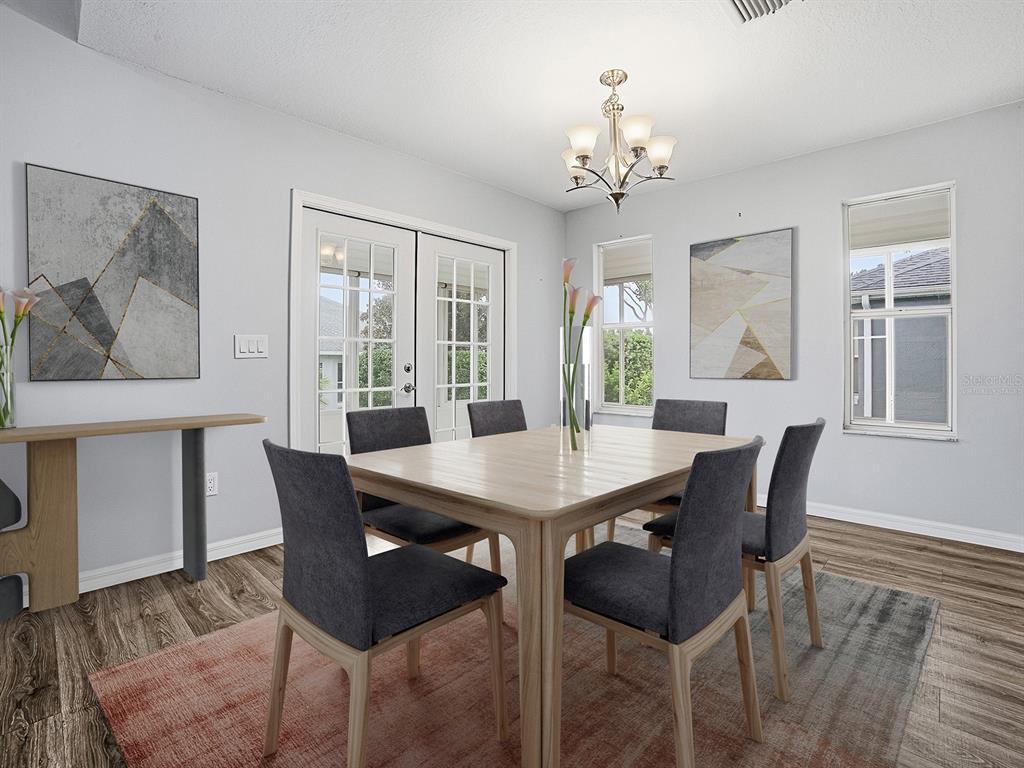 A dining room features a light wood table, six gray chairs, and two abstract wall paintings — 1322 GUERRA AVENUE, THE VILLAGES, FL