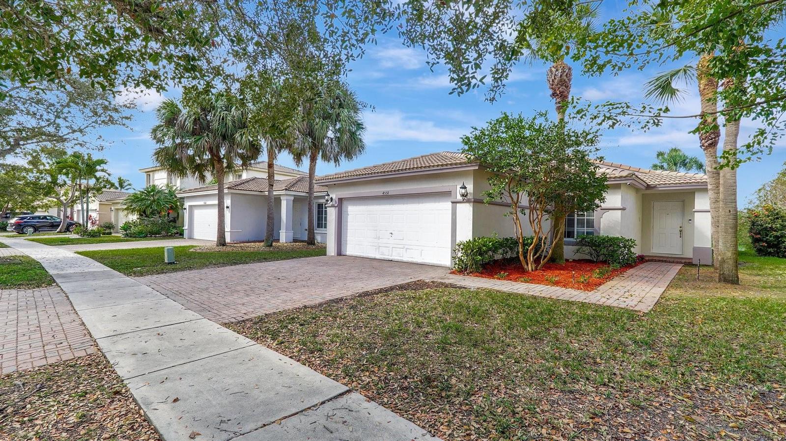 A single-story suburban house with a white garage, paved driveway, and palm trees — 4558 SW 125th Lane, Miramar FL 33027, MIRAMAR, FL