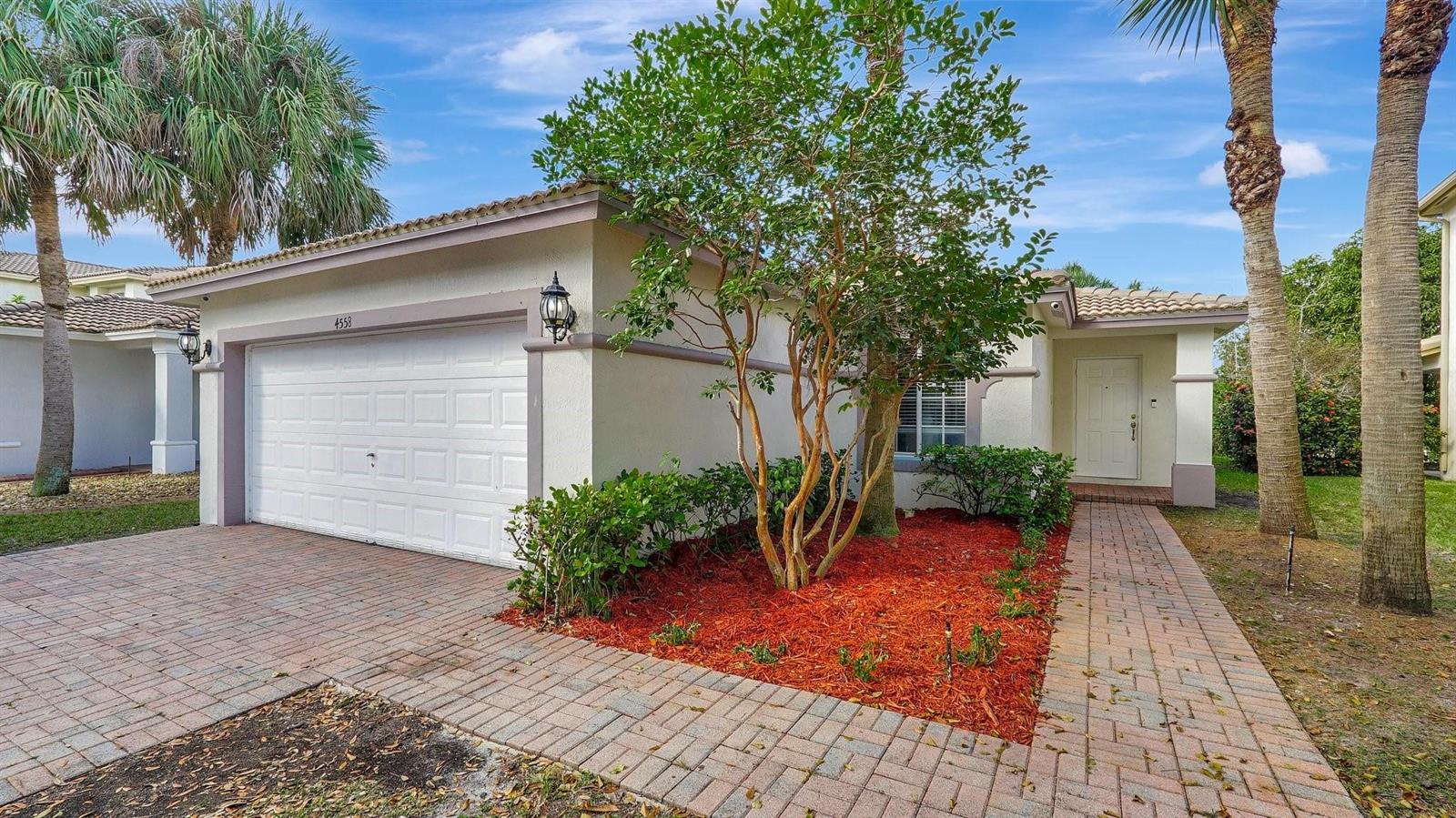 A single-story house with a white garage, brick paver driveway, and a small front garden — 4558 SW 125th Lane, Miramar FL 33027, MIRAMAR, FL