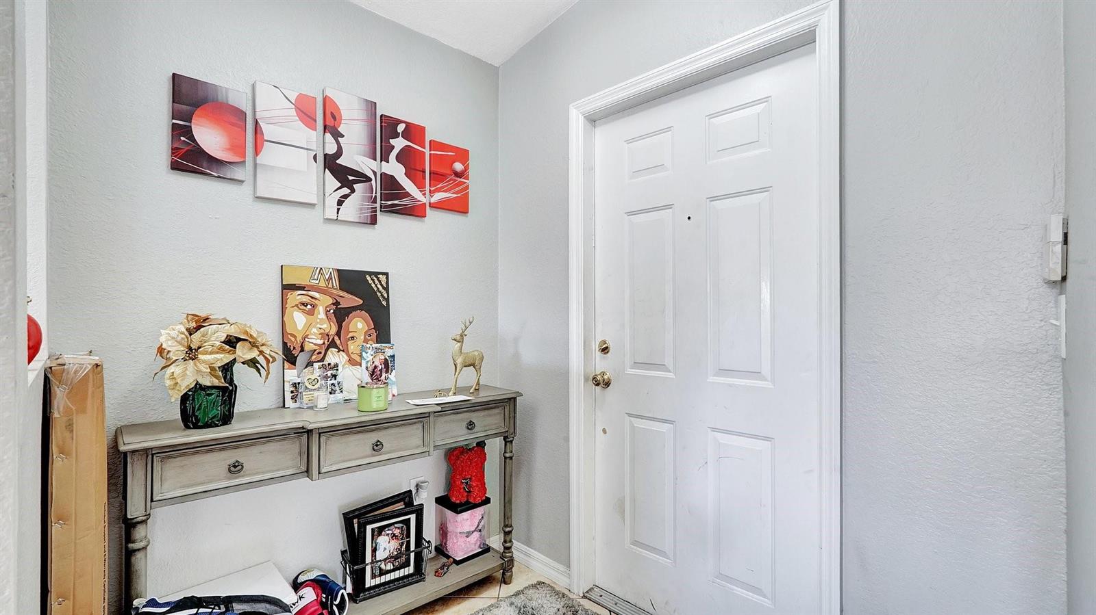 An entryway features a gray console table, wall art, and a white front door — 4558 SW 125th Lane, Miramar FL 33027, MIRAMAR, FL