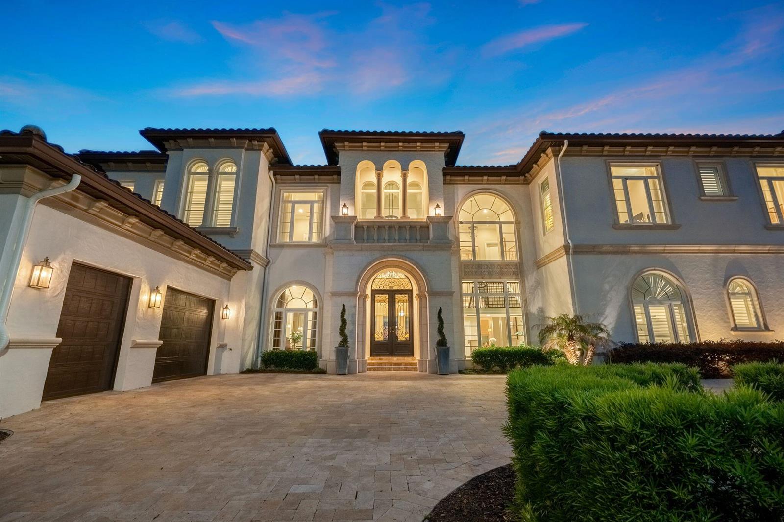 A two-story Mediterranean-style home with a paved driveway, arched windows, and a dark double-door entrance — 430 Muirfield Loop, Kissimmee FL 34747, KISSIMMEE, FL