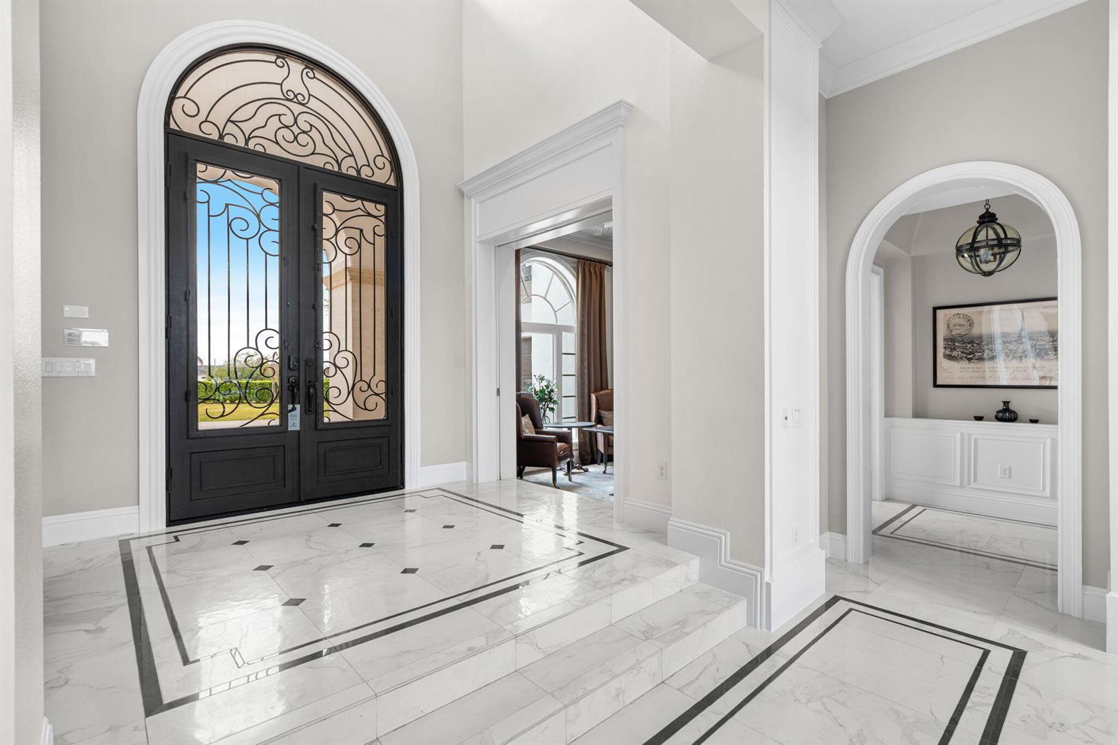 A grand foyer features marble floors, a raised entry, and a large arched iron door — 430 Muirfield Loop, Kissimmee FL 34747, KISSIMMEE, FL