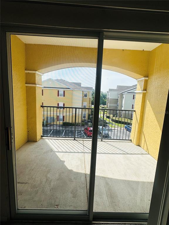 A view from inside through a sliding glass door onto a covered concrete balcony — 8124 CLAIRE ANN DRIVE UNIT 305, ORLANDO, FL