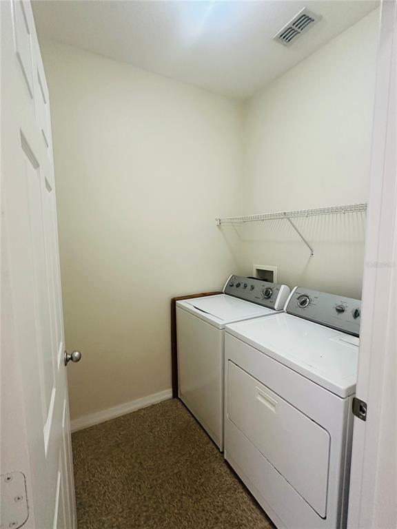 A laundry closet contains a white washer and dryer beneath a wire shelf — 8124 CLAIRE ANN DRIVE UNIT 305, ORLANDO, FL