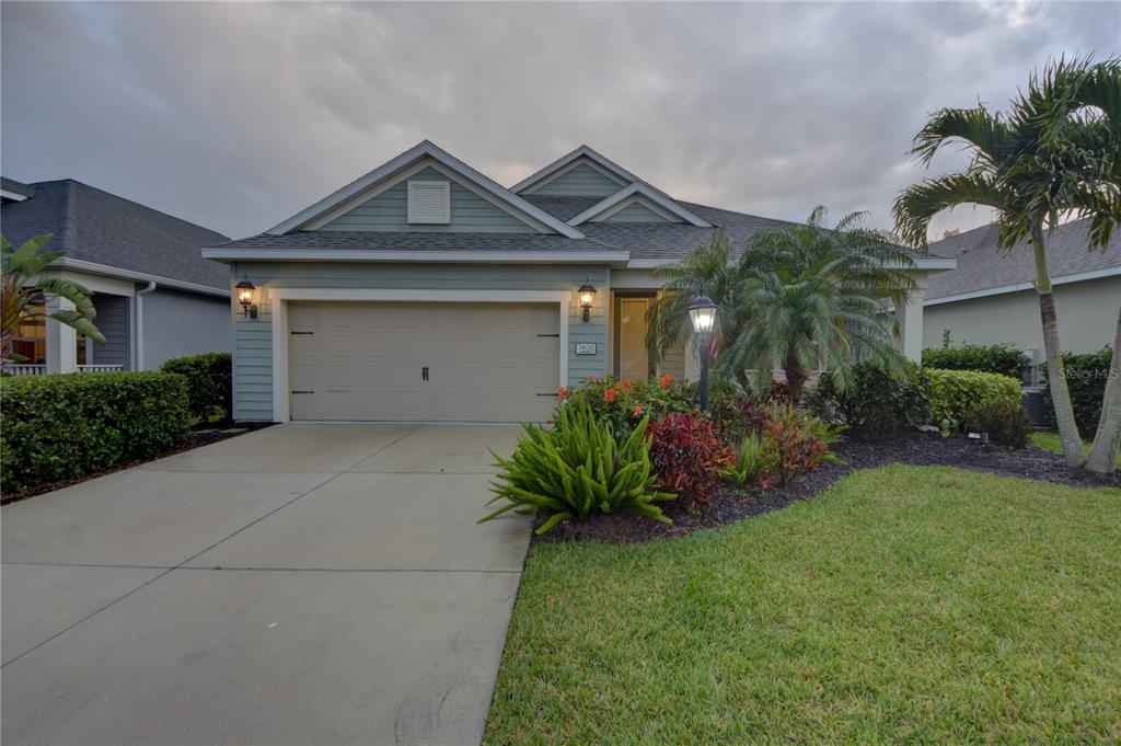 A single-story house with light blue siding, a two-car garage, and a landscaped front yard — 7408 RIDGELAKE CIRCLE, BRADENTON, FL