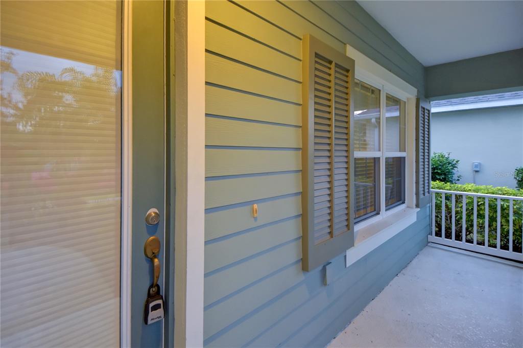 A view of a covered porch with light blue siding, a window, and a front door — 7408 RIDGELAKE CIRCLE, BRADENTON, FL