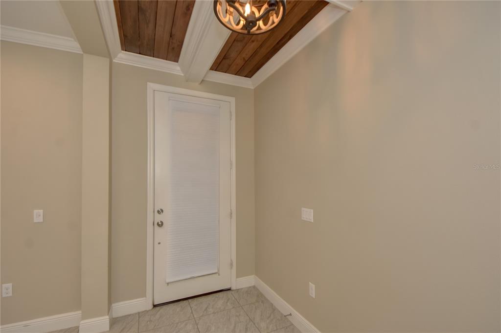 A small room features a white door, light-colored tile flooring, and a wood-paneled ceiling — 7408 RIDGELAKE CIRCLE, BRADENTON, FL