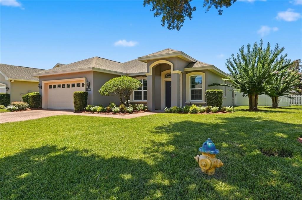 A single-story house with a tan exterior, a two-car garage, and a front lawn — 3221 OAK TREE LANE, WINTER HAVEN, FL